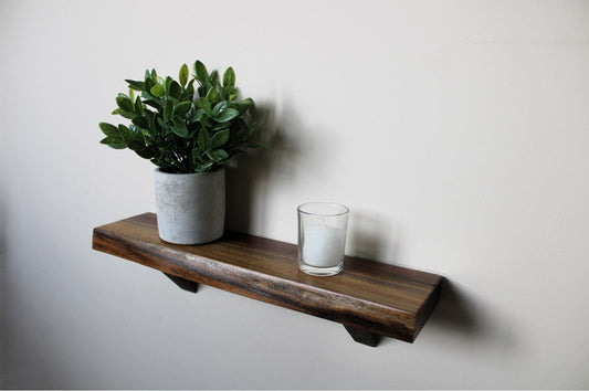 no-drill walnut floating shelf mounted on beige wall with plant and candle