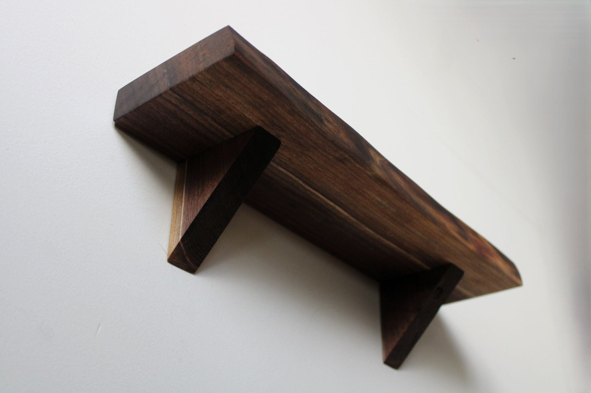 Underside view of walnut floating shelf showing suppor brackets